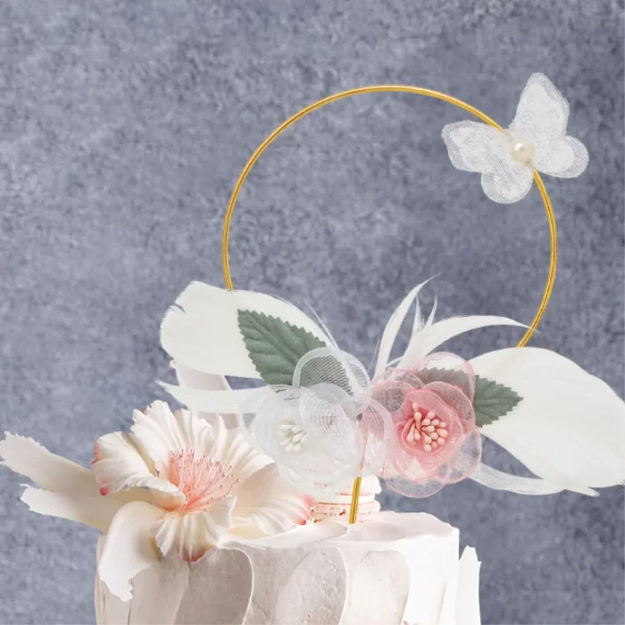 Este topo de bolo apresenta um belo design de flores de metal e penas de ouro